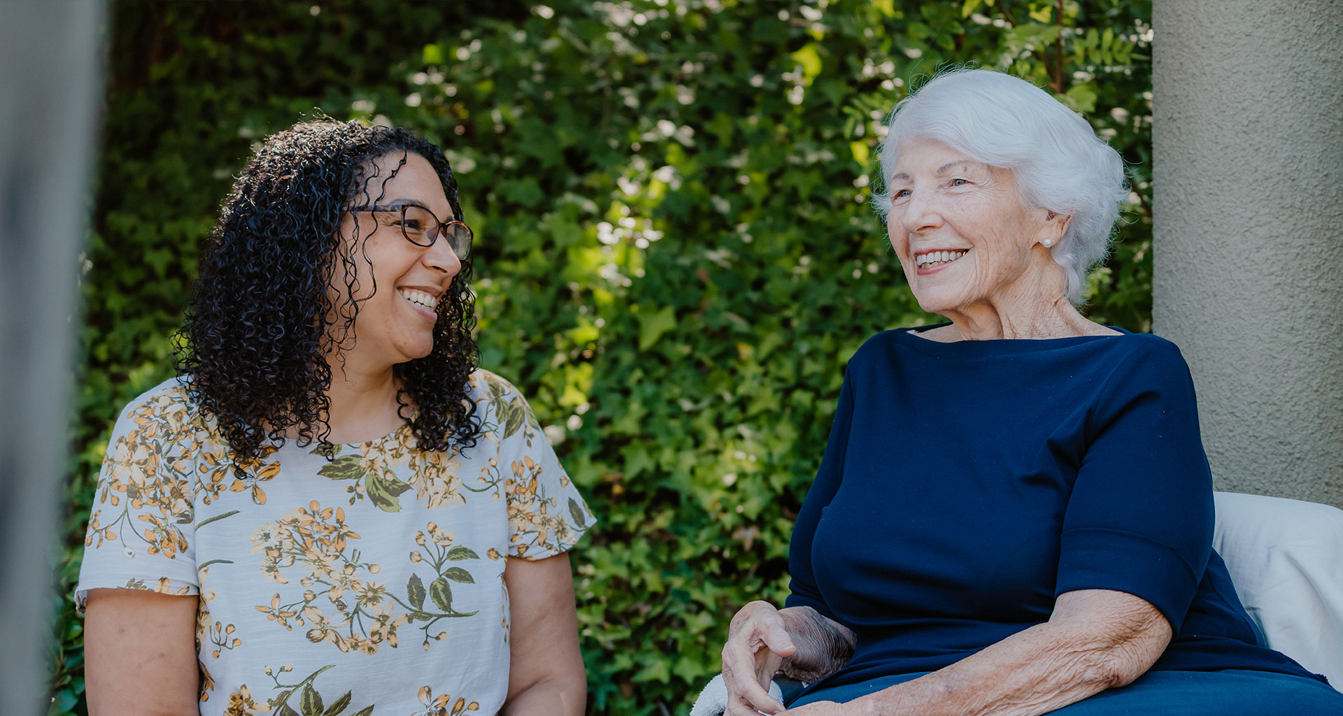 A senior woman and her caretaker laugh together