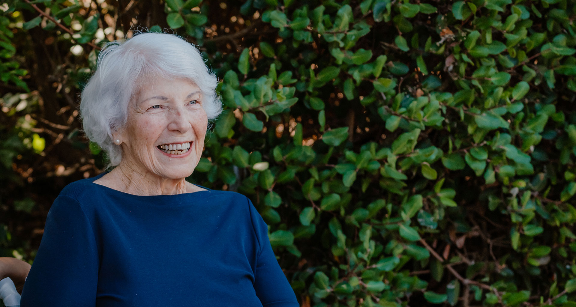 A senior woman laughs outdoors
