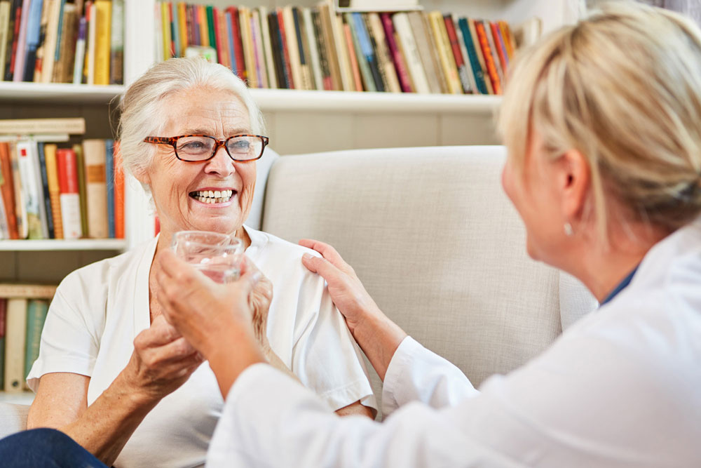 A doctor hands a senior woman a glass of water