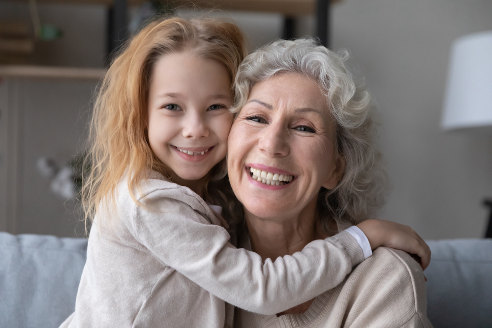 A senior woman and her granddaughter smiling together