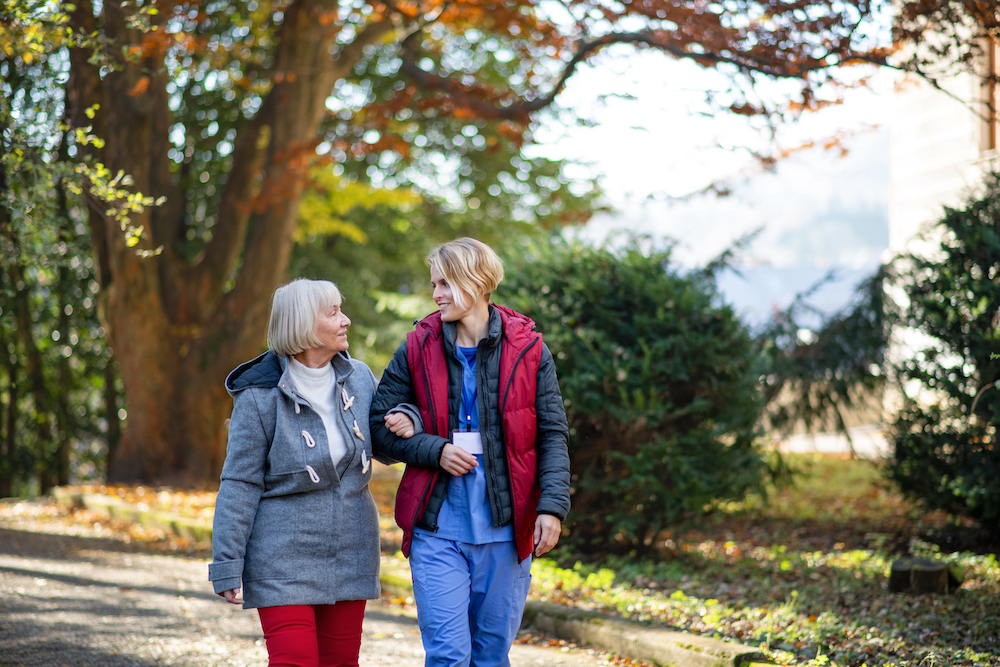 A senior woman on a walk with a caregiver