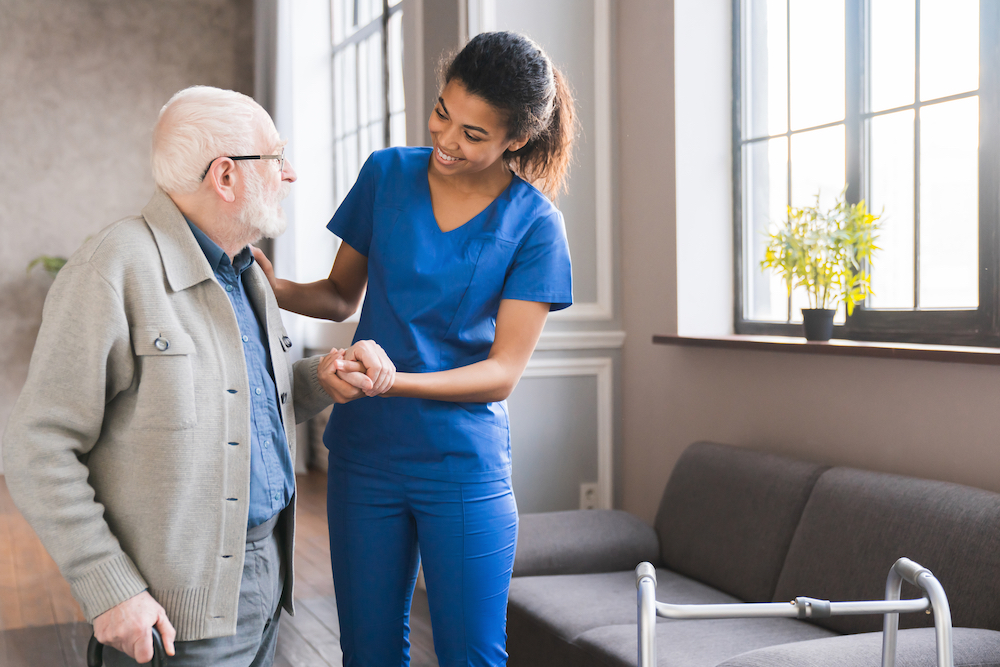 A caregiver at respite care services helps a senior man stand up