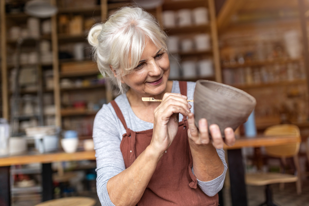 A senior woman sculpts pottery