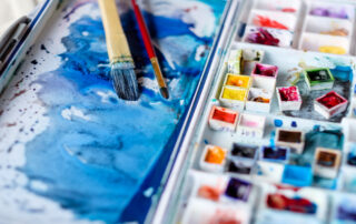 A watercolor paint tray with various paints